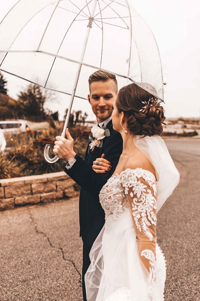 Bride and Groom looking at each other while walking under a clear umbrella