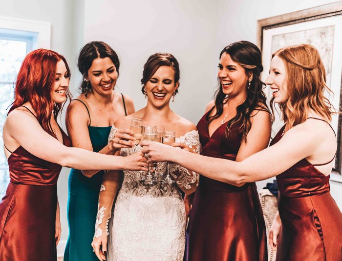Bride and Bridesmaids clinking champagne flutes together in a 'cheers'