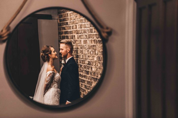 Reflection of the bride and groom in a hanging round mirror