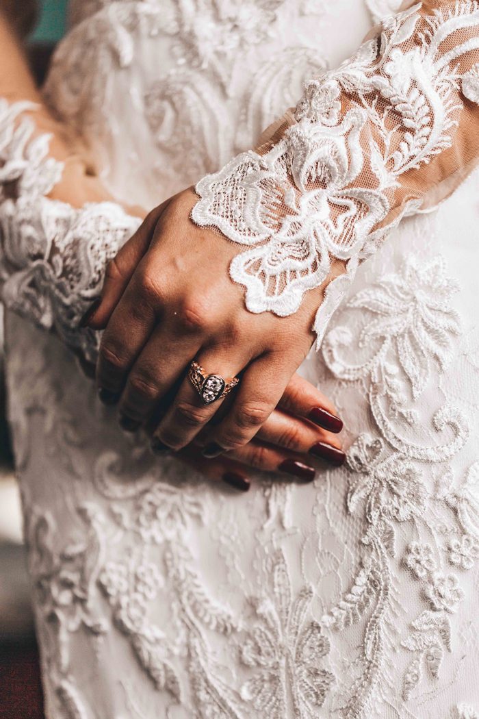Brides holding her hands in front of her lace wedding down showing her vintage wedding ring